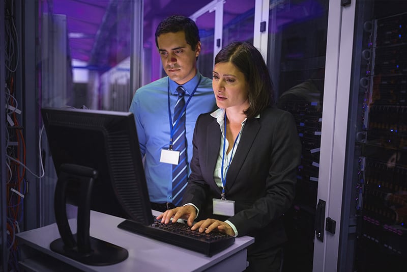 Two people stood in a data centre, looking at big data analytics 