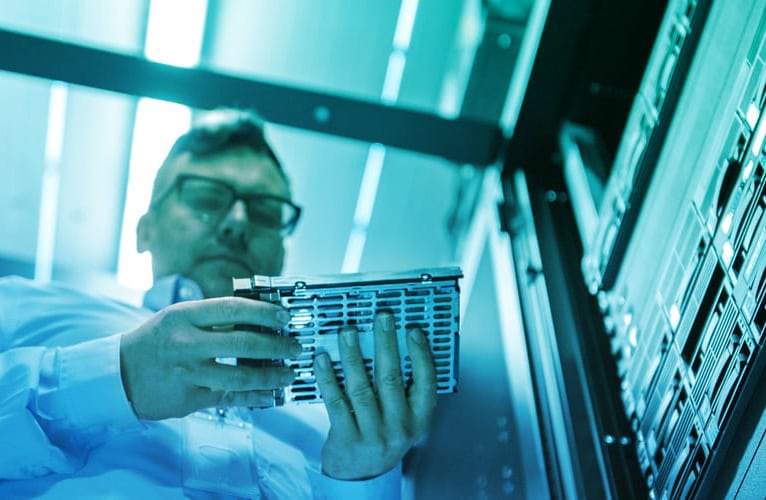 Low Angle Shot In Fully Working Data Center IT Engineer Installs Hard Drive into Server Rack. Detailed and Technically Accurate Footage.